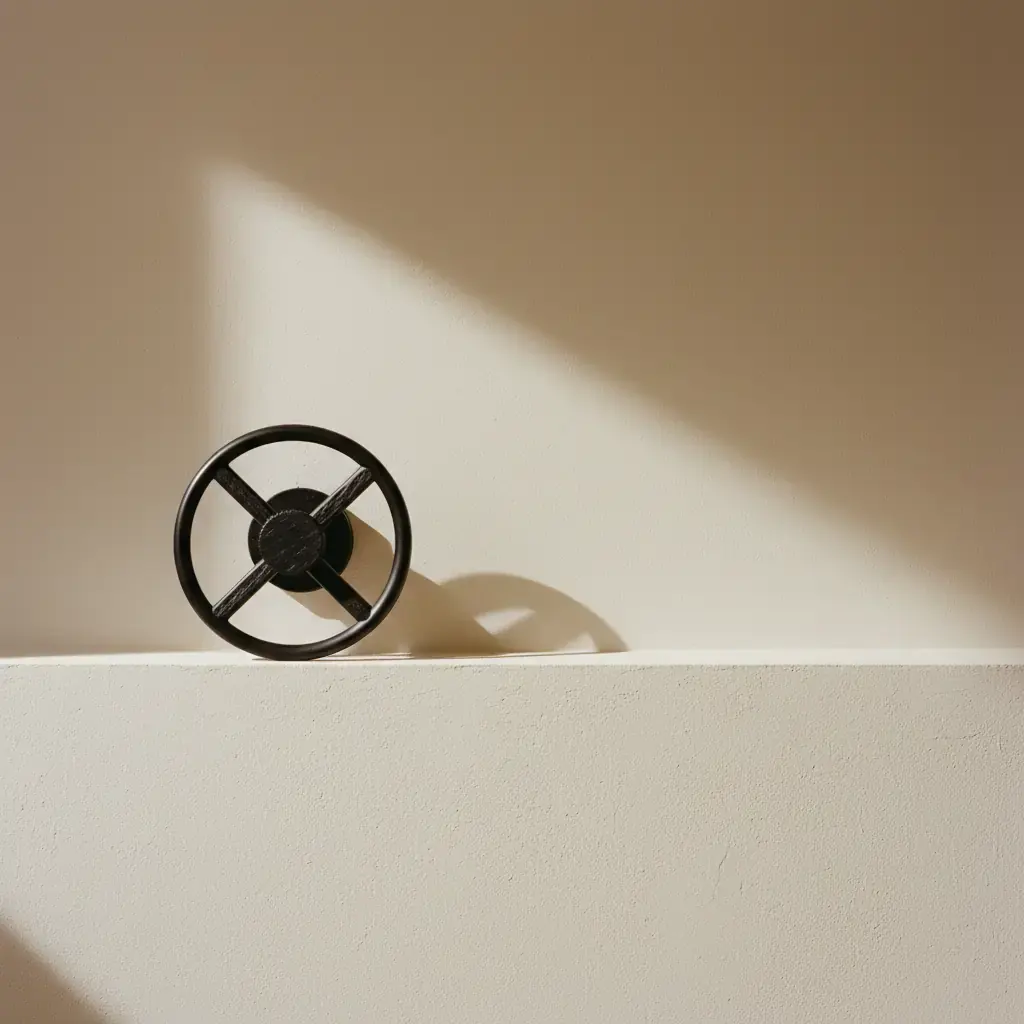 A black four-spoke wheel resting on a plaster ledge, a hard shaft of sunlight on the wall behind